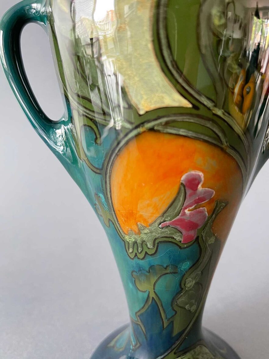 Deze vaas is 23 cm hoog en heeft twee oren. Het is model 55 van Plateelbakkerij Zuid-Holland uit Gouda en is beschilderd door Jan van Schaick.