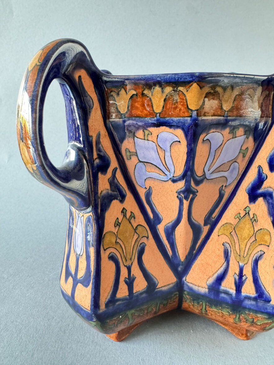 Holland Utrecht cachepot, model 177 van 18 cm hoog en 22 cm breed. Gemaakt rond 1900 en beschilderd met een floraal decor in blauw, paars en oranje tinten.