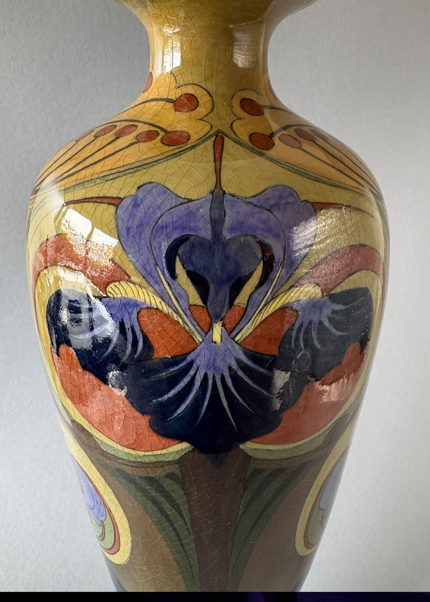 Vaas, model 112 van Firma Jb Vet uit Purmerend. 43 cm hoog en 13 cm breed met een bont floraal decor met irissen, gemaakt tussen 1903 en 1907.