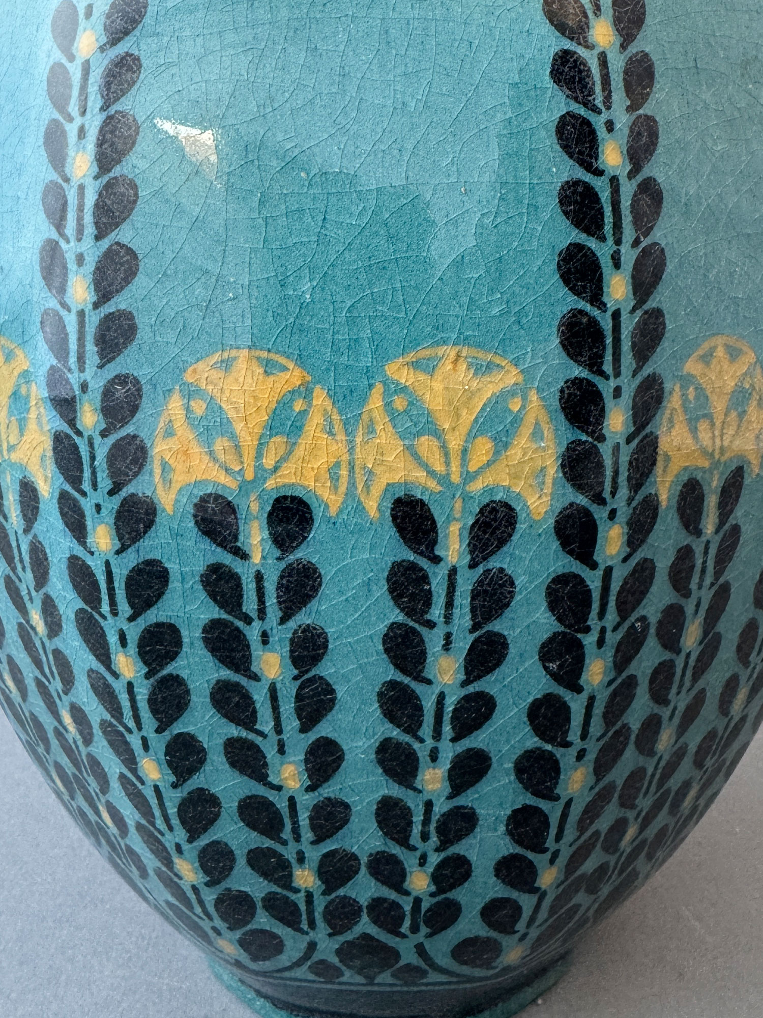 Vaas van De Distel Amsterdam, model 269, beschilderd met gestilleerde bloemen en takken in zwart en oker tegen een donker turquoise achtergrond, ontworpen door Bert Nienhuis, omstreeks 1905.