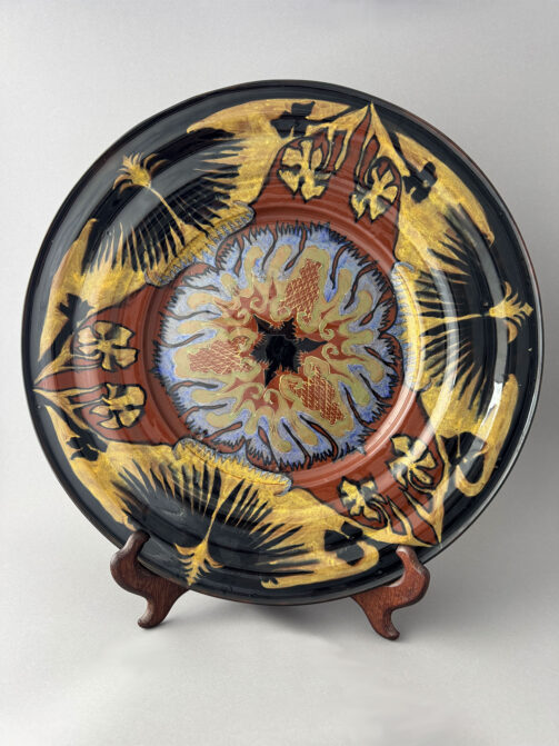 Wandbord van 43,5 cm breed, gemaakt door Plateelbakkerij Rozenburg uit Den Haag in mei 1893. Beschilderd door F. Mansveld, mogelijk naar een ontwerp van Theo Colenbrander.