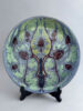 Holland Utrecht wandbord van bijna 30 cm breed met een abstract floraal decor in lila en groen, gemaakt tussen 1895-1904.