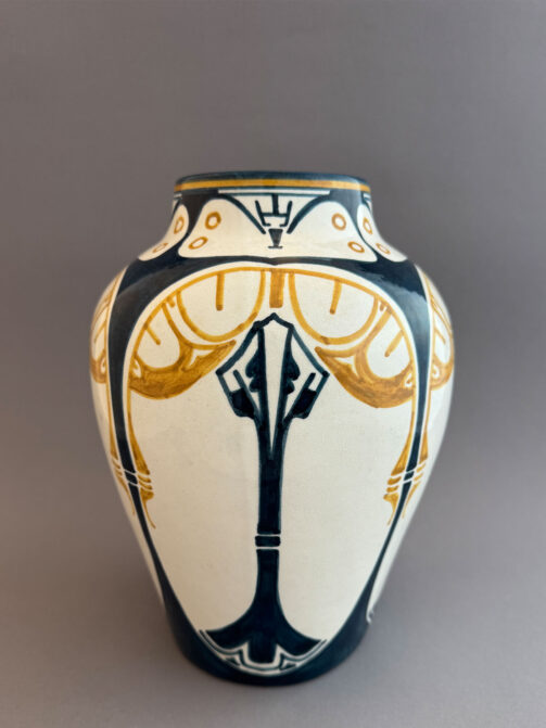 Vaas van DKP, de Dordtsche Kunstpotterij uit Dordrecht, gemaakt tussen 1903 en 1908. Dit is model 26, beschilderd met een geometrisch decor in blauw en geel, tegen een witte achtergrond.